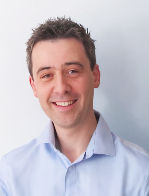 A man in a blue shirt smiling at the camera.